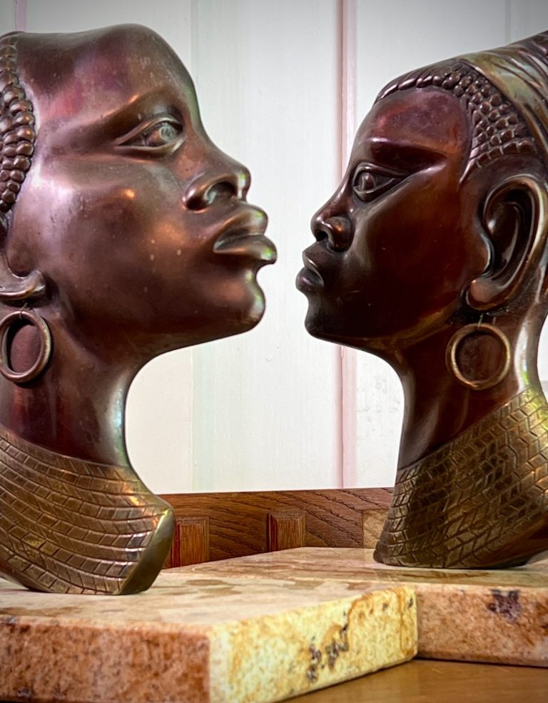 Pair of bronze African busts, Hagenauer Style, mounted on separate stone bases, mid-century decorative sculptures