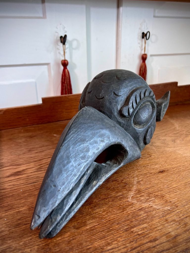 Carved wooden bird mask with prominent beak and decorative wings